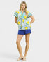 Woman wearing a colorful top and blue shorts on a white background