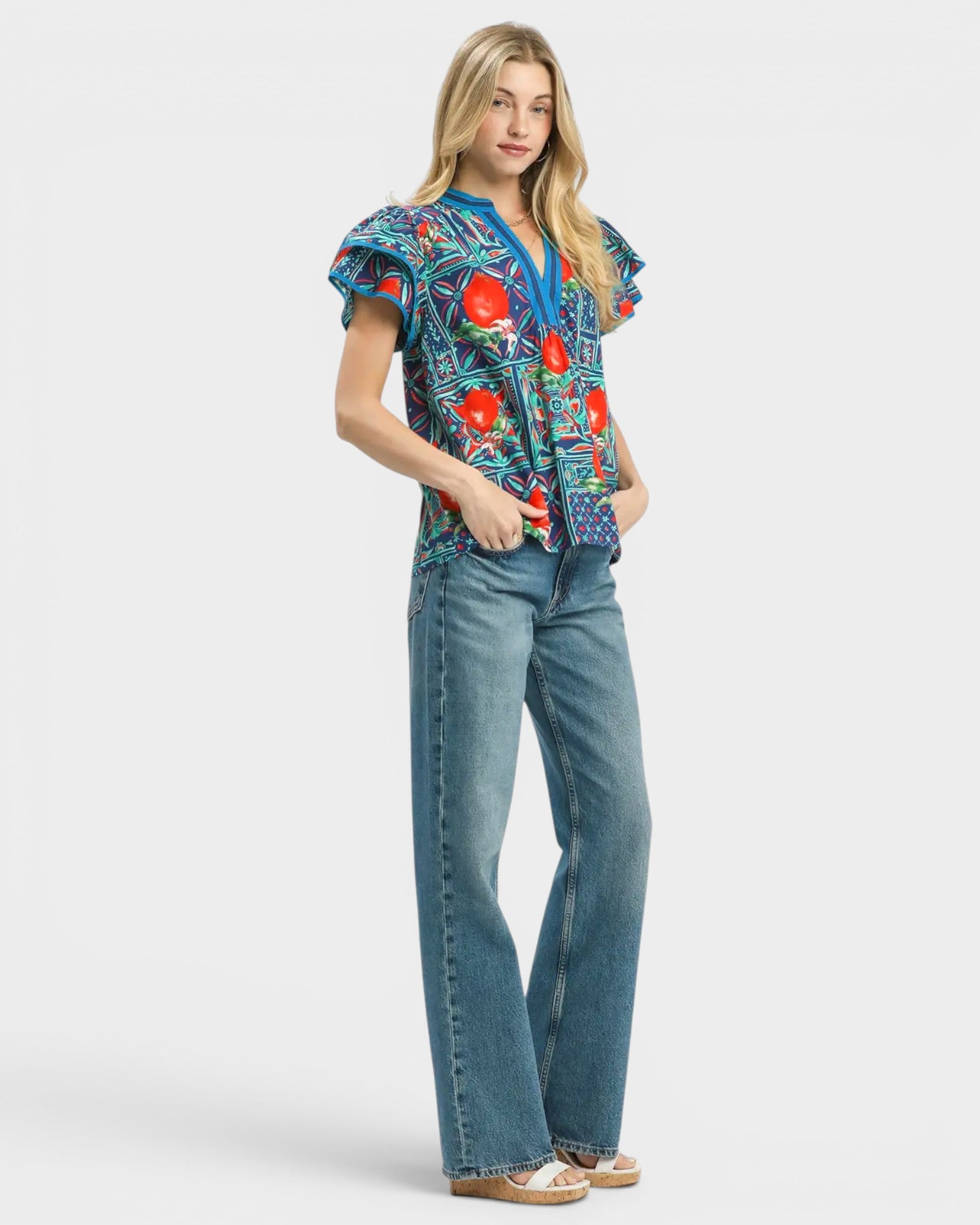 Woman wearing a colorful floral blouse and blue jeans on a white background