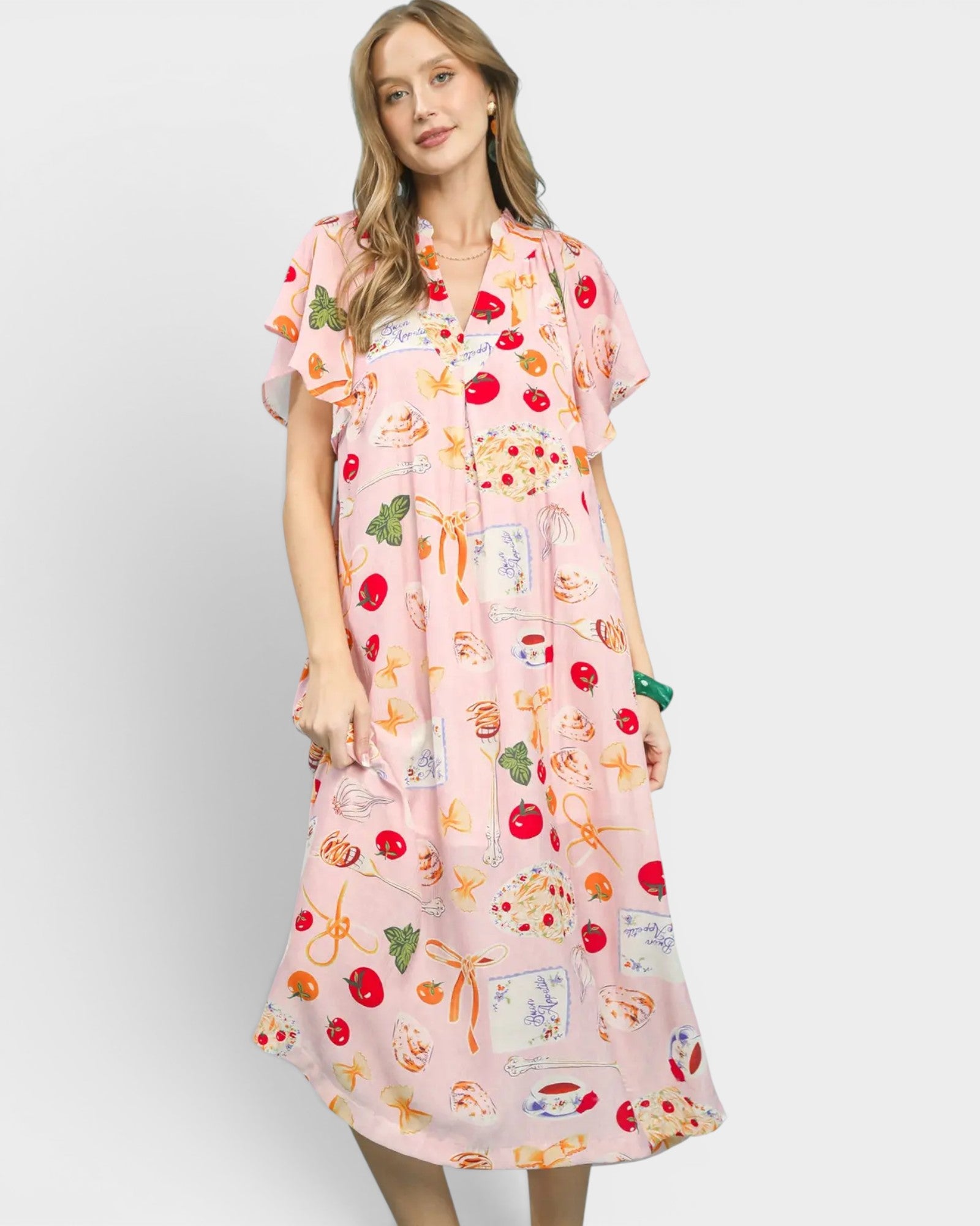 Woman wearing a pink dress with colorful fruit pattern on a white background