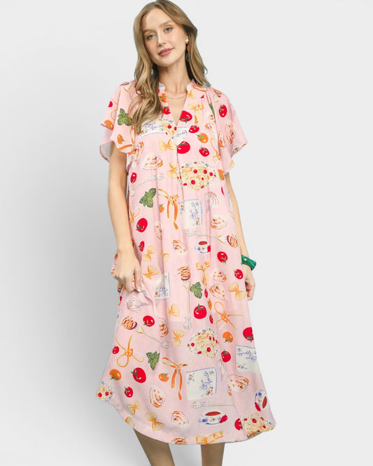 Woman wearing a pink dress with colorful fruit pattern on a white background