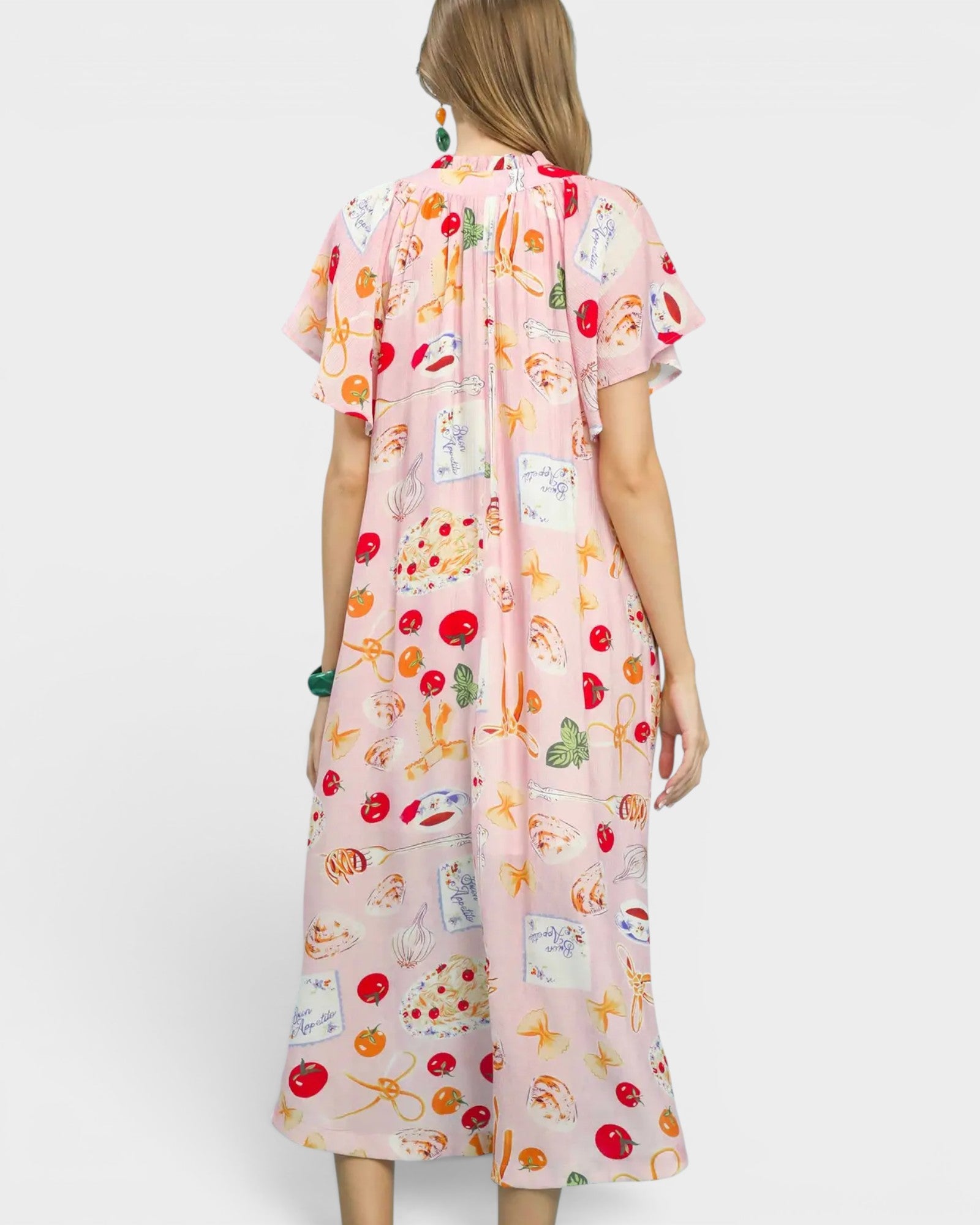 Woman wearing a pink dress with colorful prints on a white background
