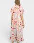 Woman wearing a pink dress with colorful prints on a white background