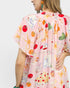 Person wearing a pink dress with colorful food print on a plain background