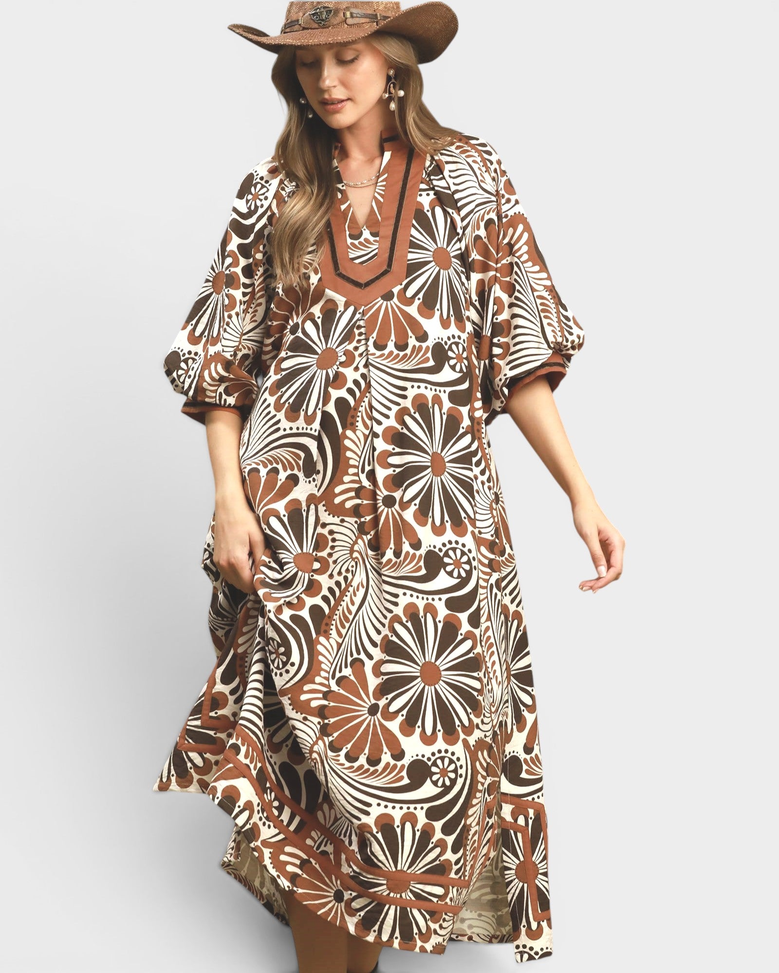 Woman wearing a patterned dress and hat on a plain background