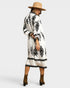 Woman wearing a white dress with black patterns and a beige hat on a white background