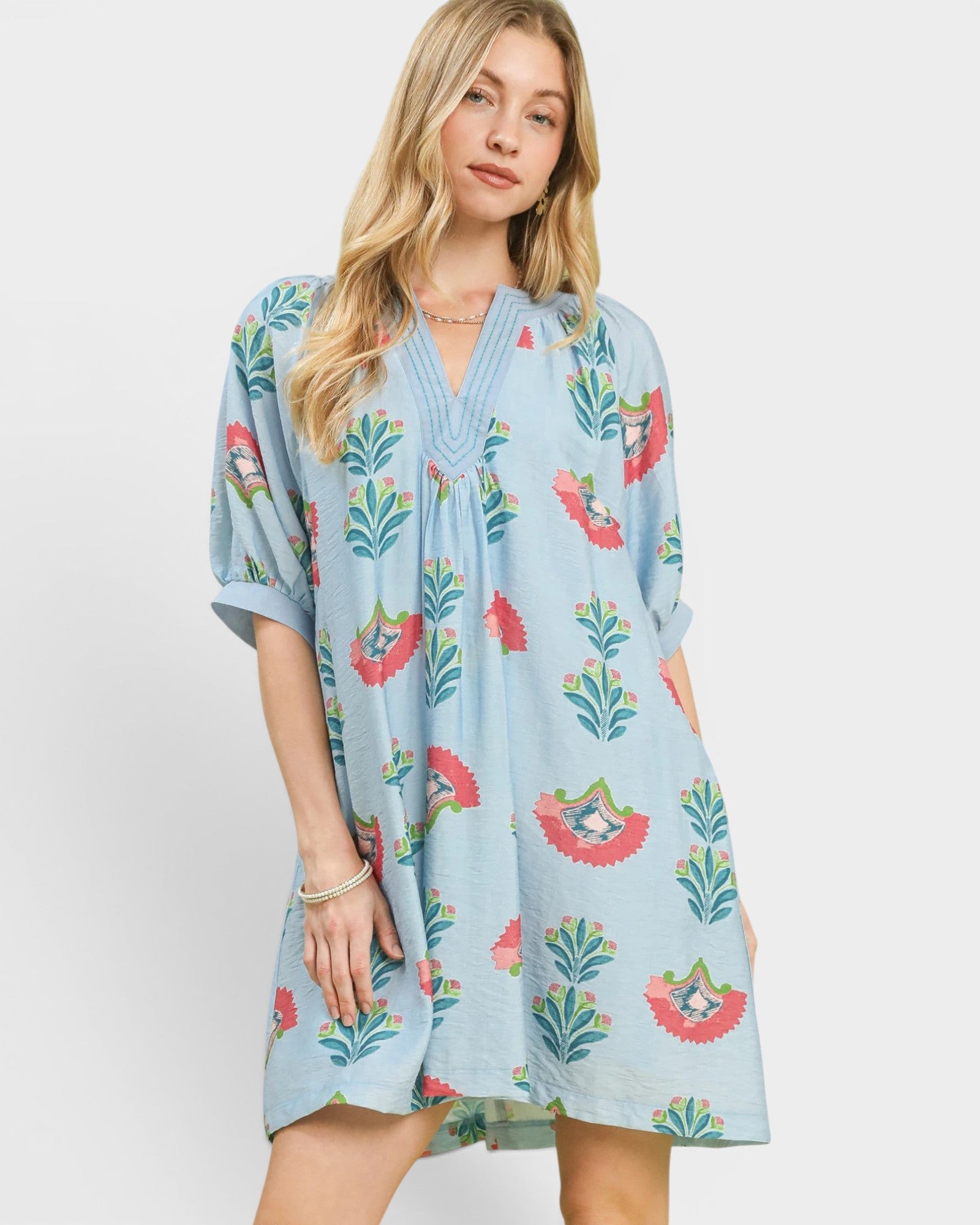Woman wearing a light blue floral dress on a white background