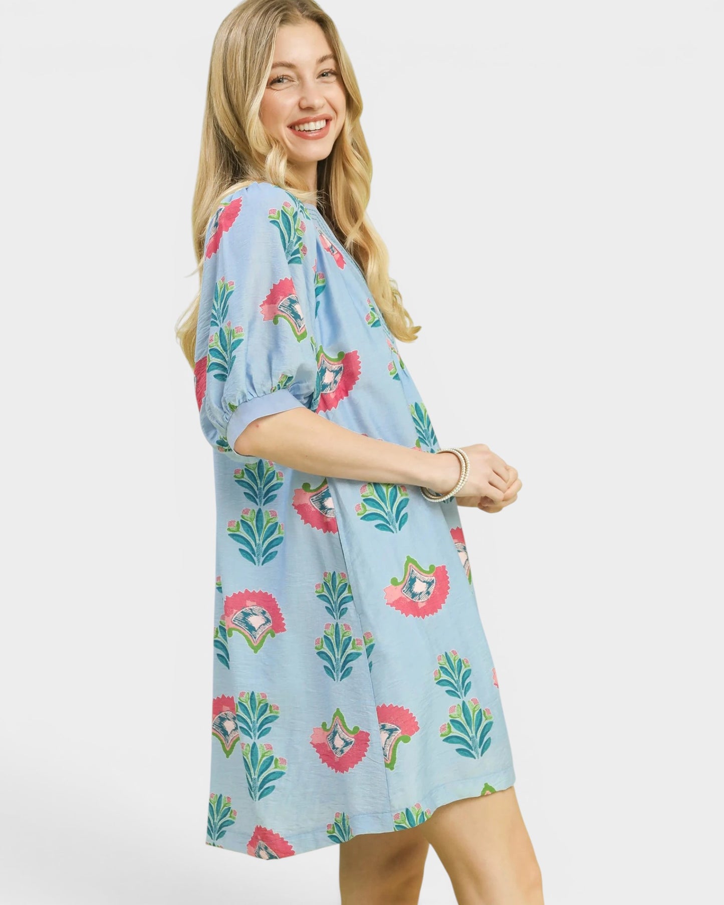 Woman wearing a light blue dress with floral patterns on a white background