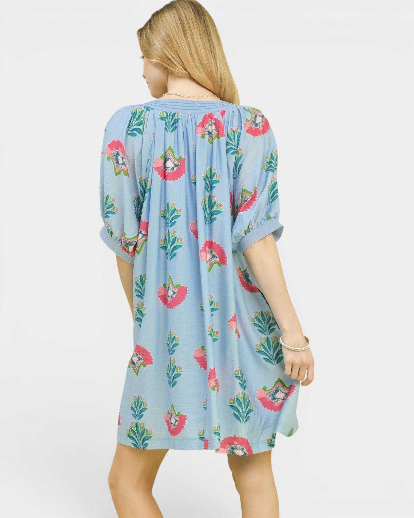 Woman wearing a light blue dress with floral patterns on a white background