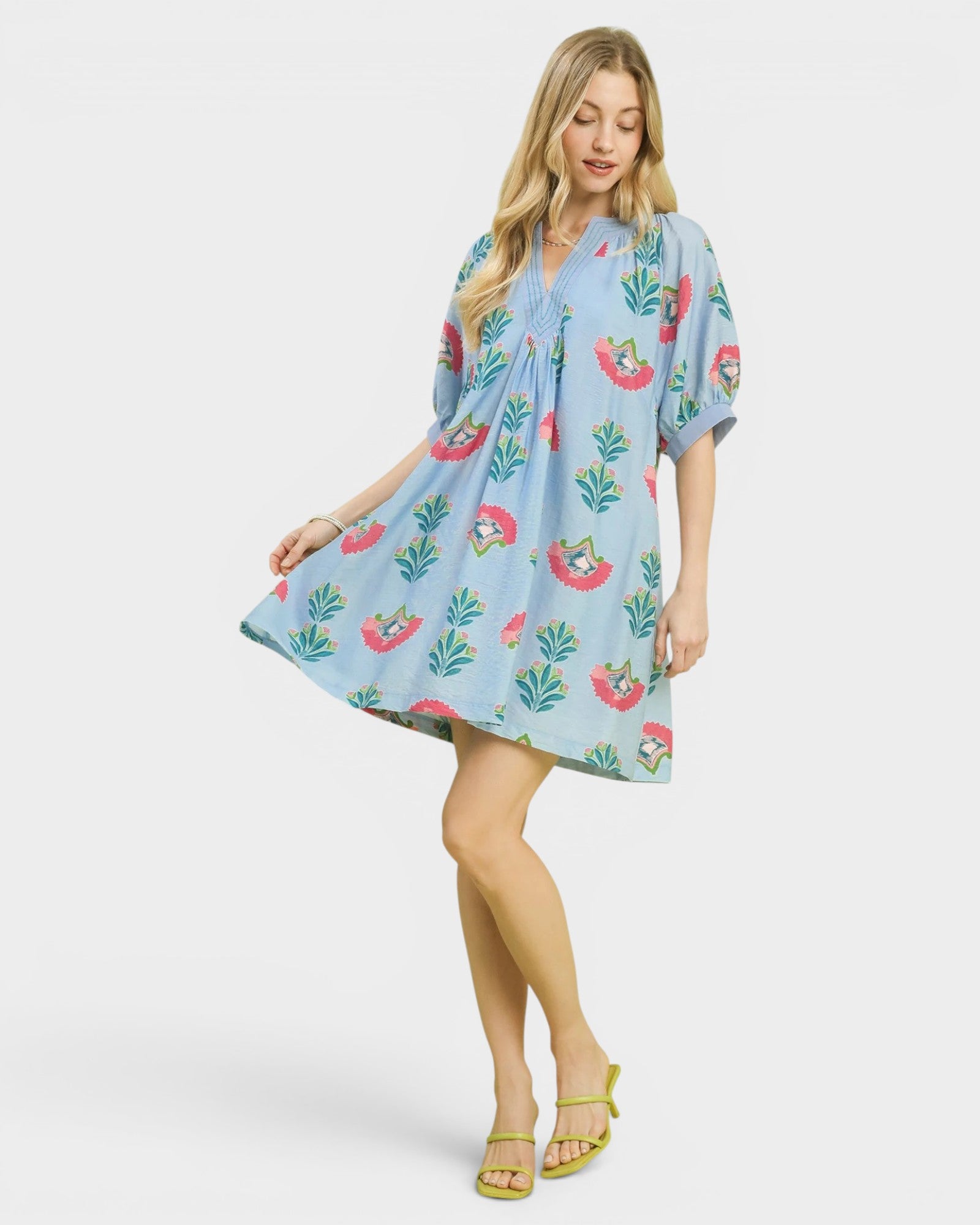 Woman wearing a light blue dress with floral patterns on a white background