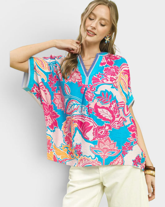 Woman wearing a colorful patterned top with a plain background