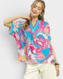 Woman wearing a colorful patterned top with a plain background