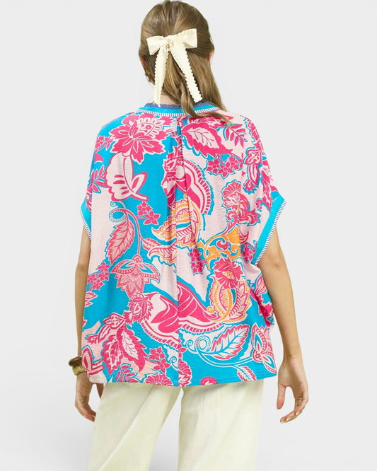 Woman wearing a colorful floral patterned top on a white background