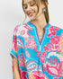 Woman wearing a colorful floral dress with a plain background
