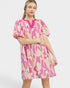 Woman wearing a pink and beige patterned dress on a white background