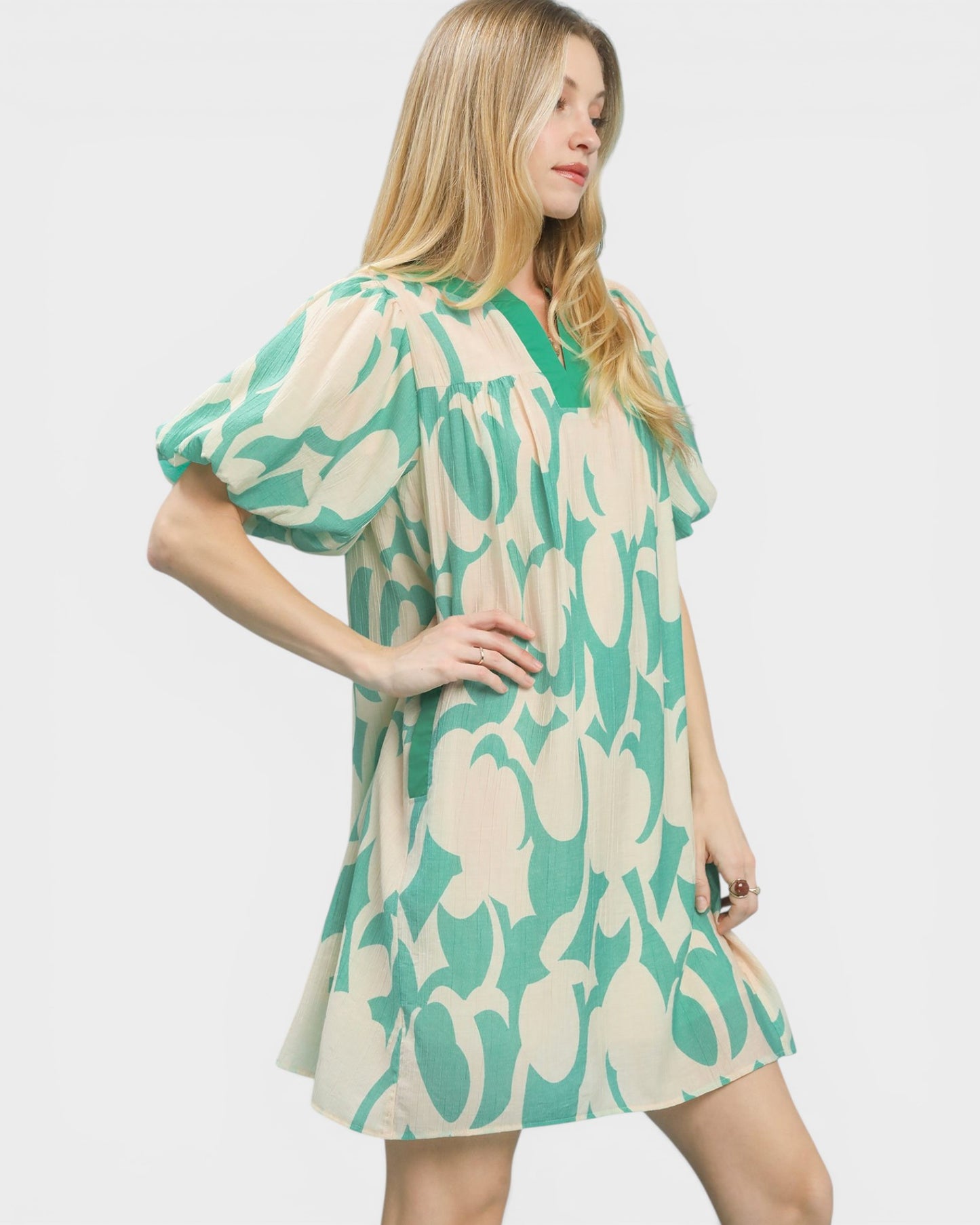 Woman wearing a green and beige patterned dress on a white background