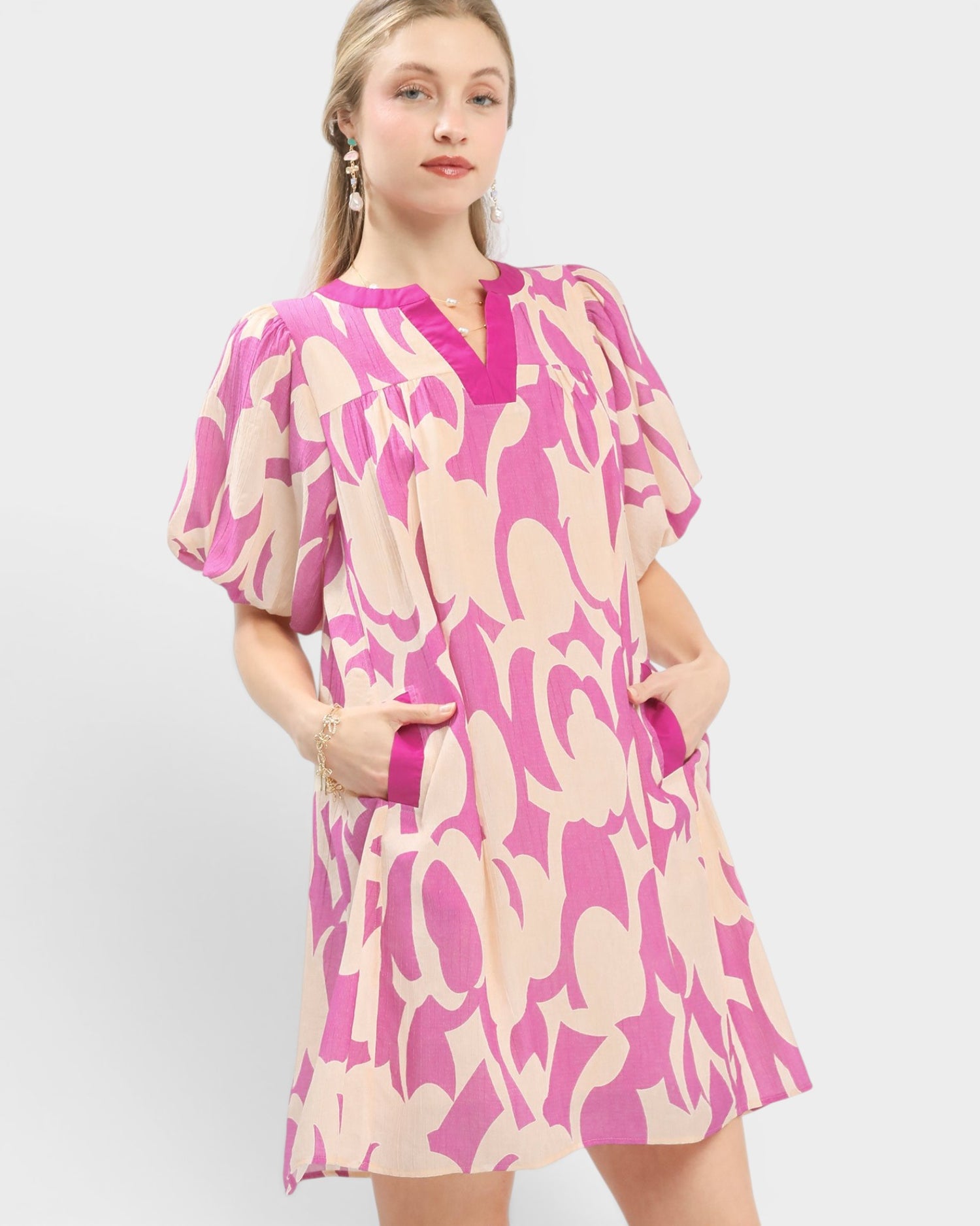 Woman wearing a pink and beige patterned dress on a white background