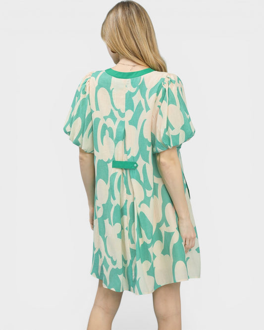 Woman wearing a green and beige patterned dress on a white background