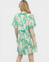 Woman wearing a green and beige patterned dress on a white background
