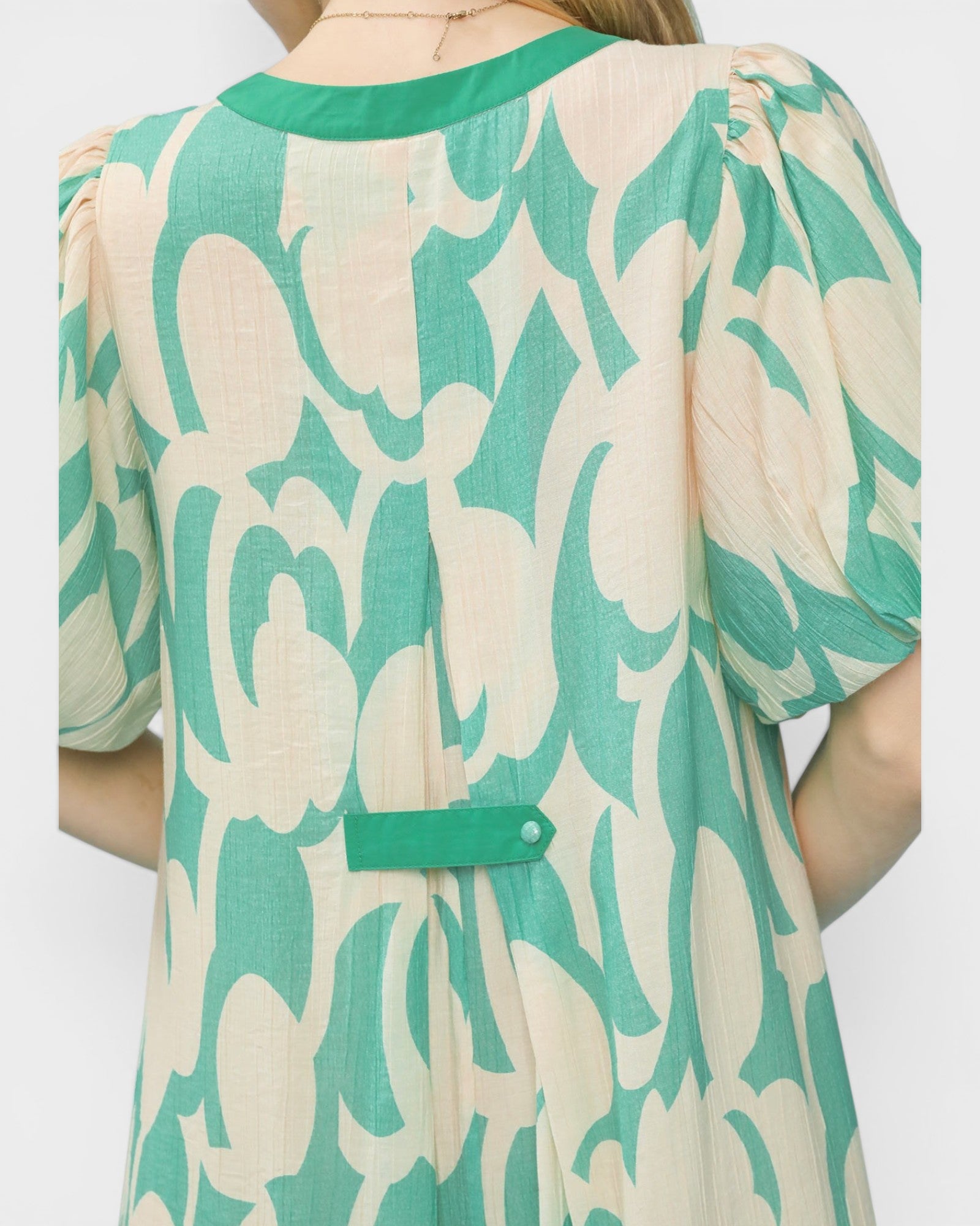 Green and beige patterned dress on a plain background