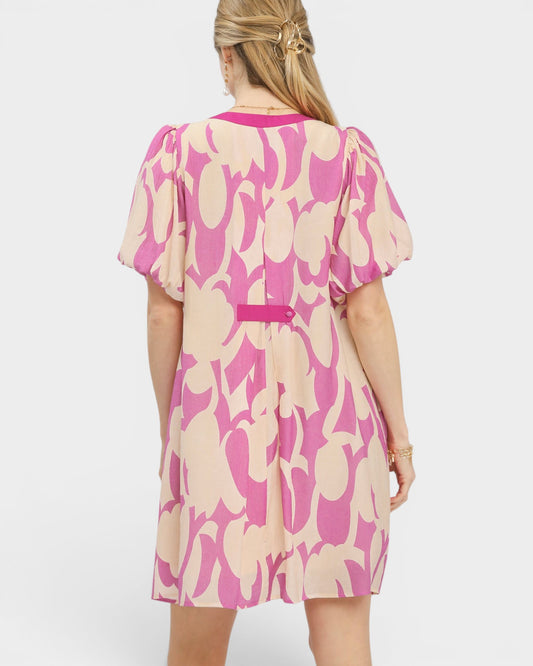 Woman wearing a pink and beige patterned dress on a white background