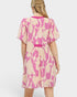 Woman wearing a pink and beige patterned dress on a white background