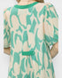 Green and beige patterned dress on a plain background