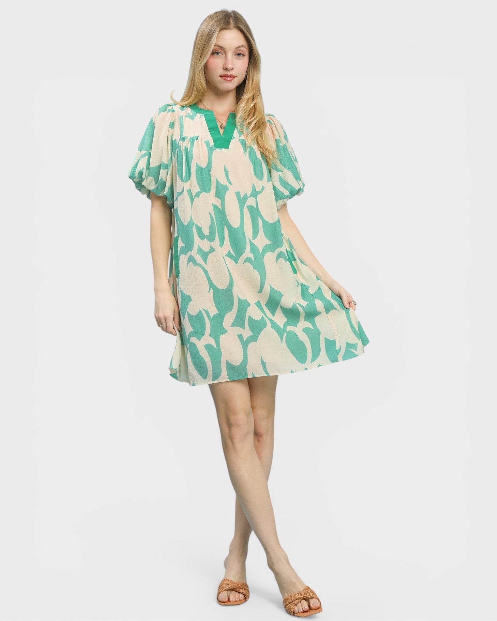 Woman wearing a green and beige patterned dress on a white background