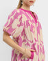 Woman wearing a pink and beige patterned dress on a white background