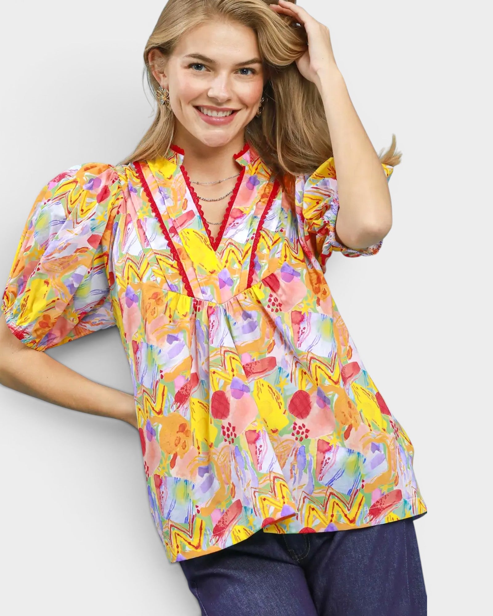 Woman wearing a colorful patterned blouse with a plain background