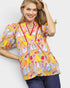 Woman wearing a colorful patterned blouse with a plain background