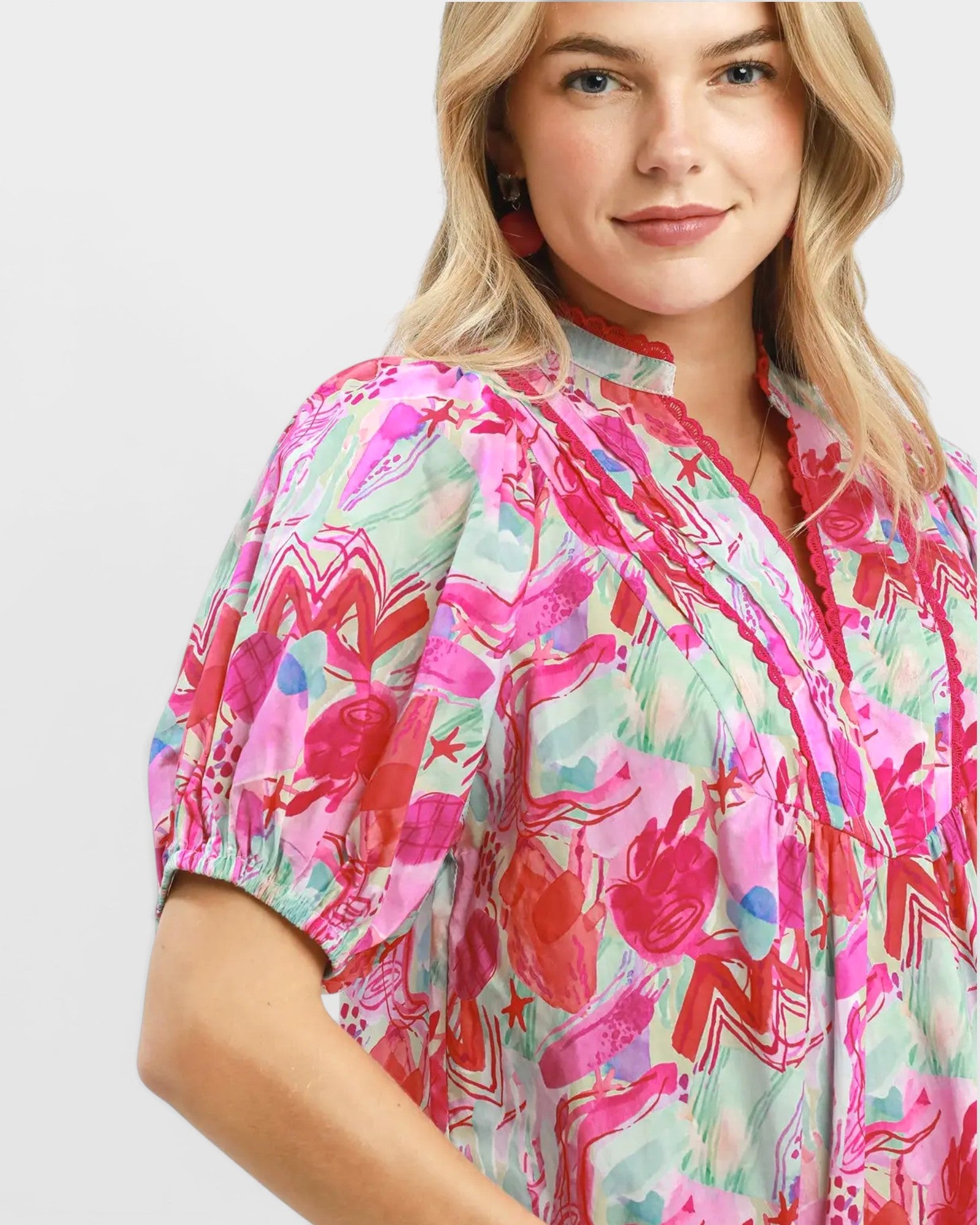 Woman wearing a colorful floral blouse on a light gray background