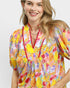 Woman wearing a colorful floral dress with a plain background