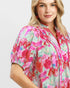 Woman wearing a colorful floral blouse on a light gray background