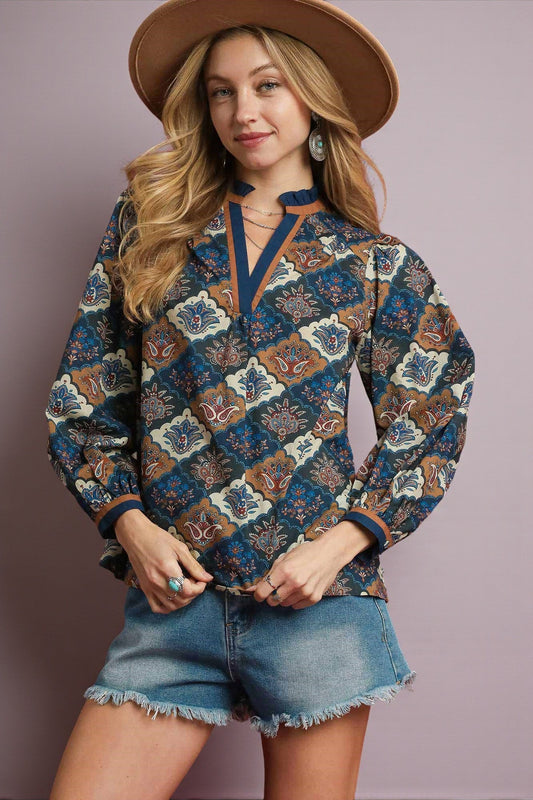 Woman wearing a patterned shirt and denim shorts with a brown hat on a plain background