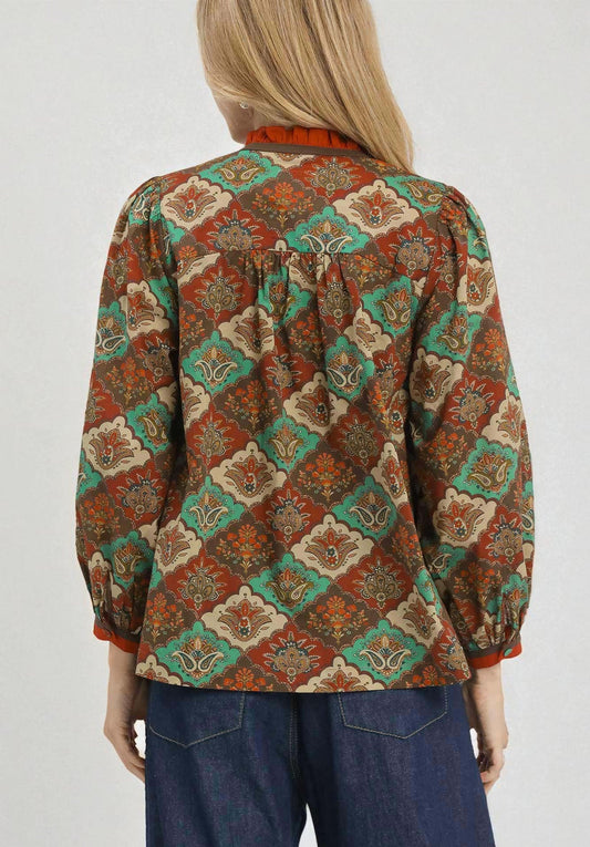 Person wearing a patterned blouse with a white background