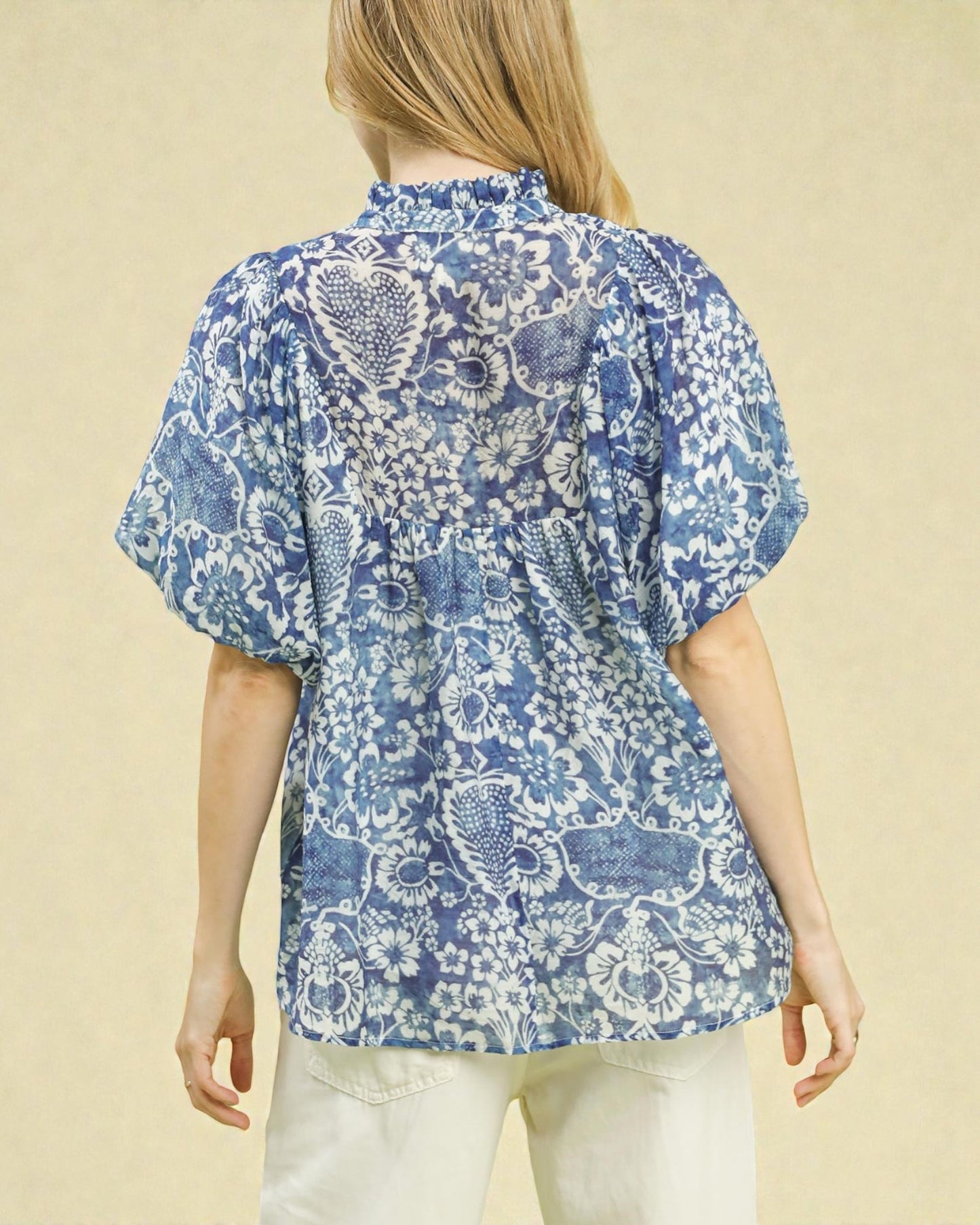 Woman wearing a blue floral patterned blouse on a beige background