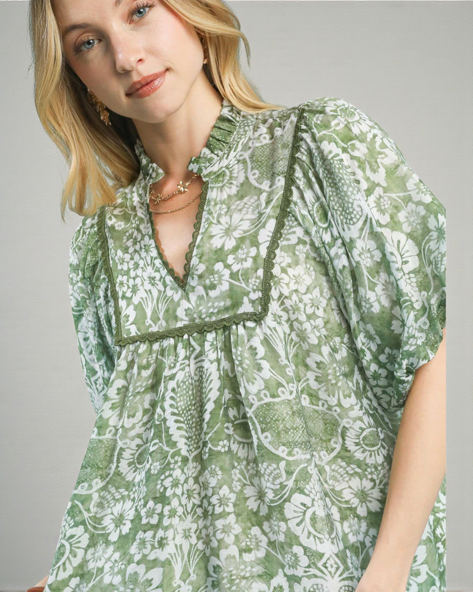 Woman wearing a green floral dress against a gray background