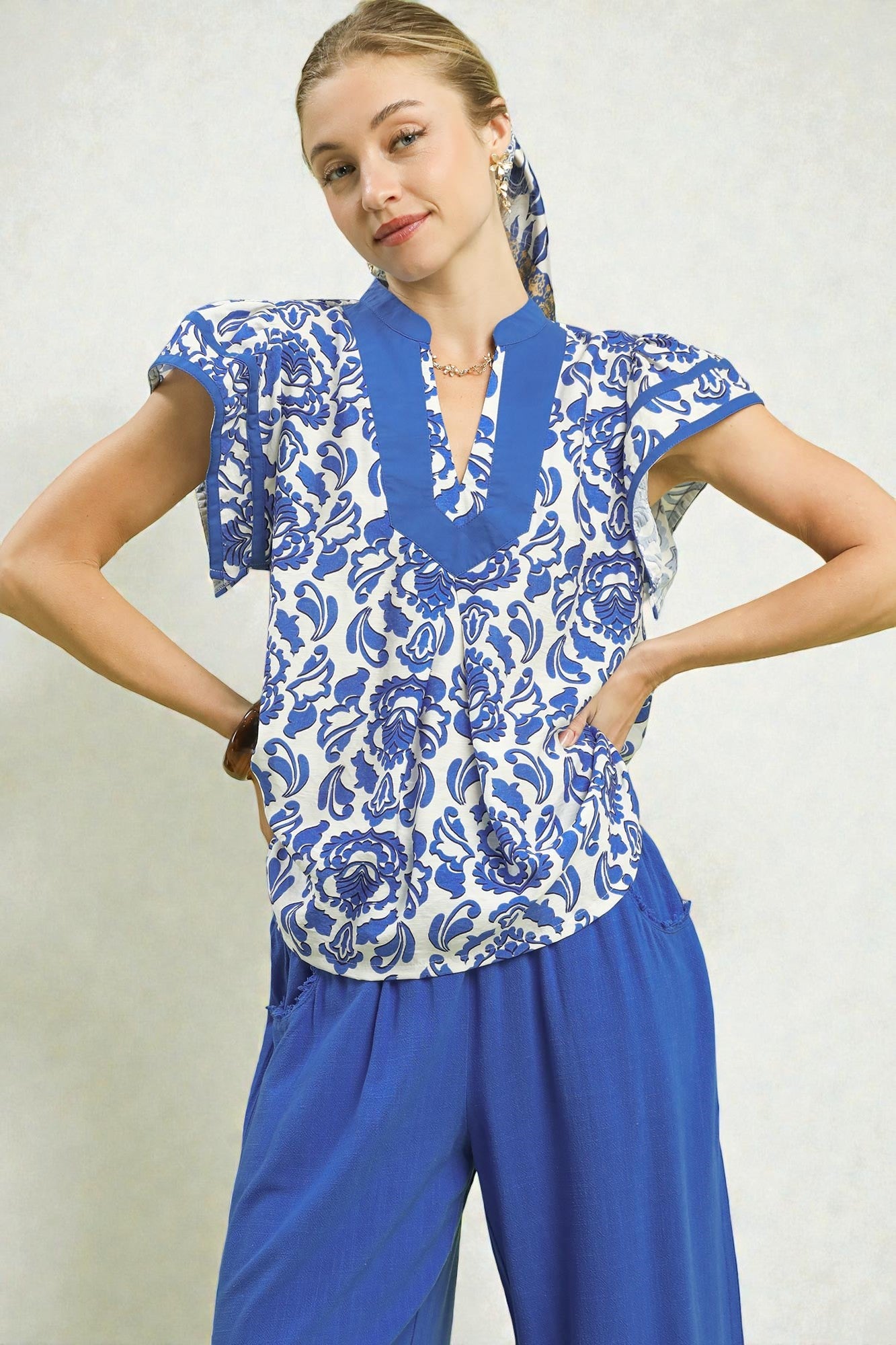 Woman wearing a blue and white floral top with matching pants on a plain background
