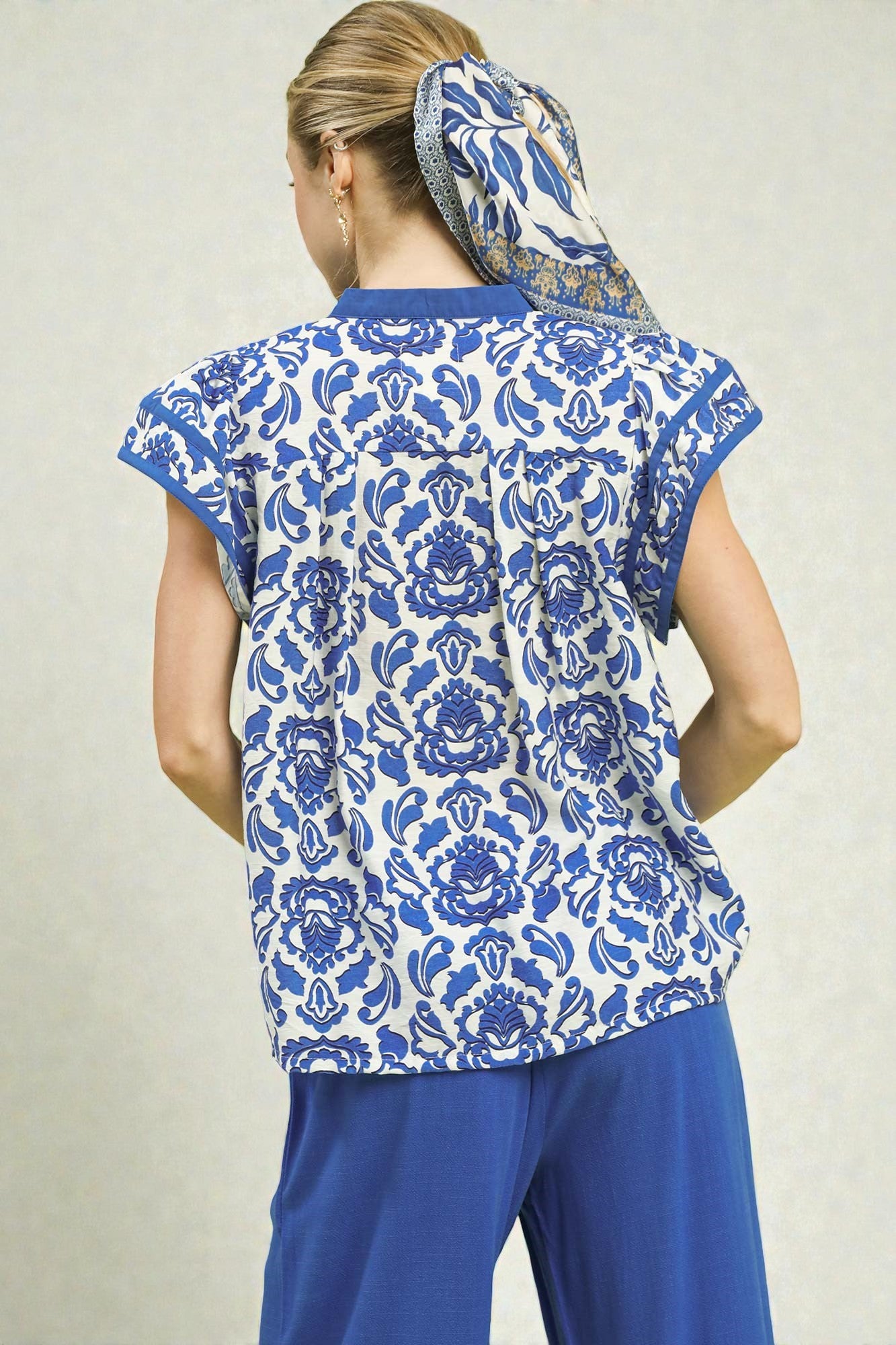 Woman wearing a blue and white patterned top with matching pants on a plain background