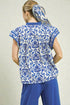 Woman wearing a blue and white patterned top with matching pants on a plain background
