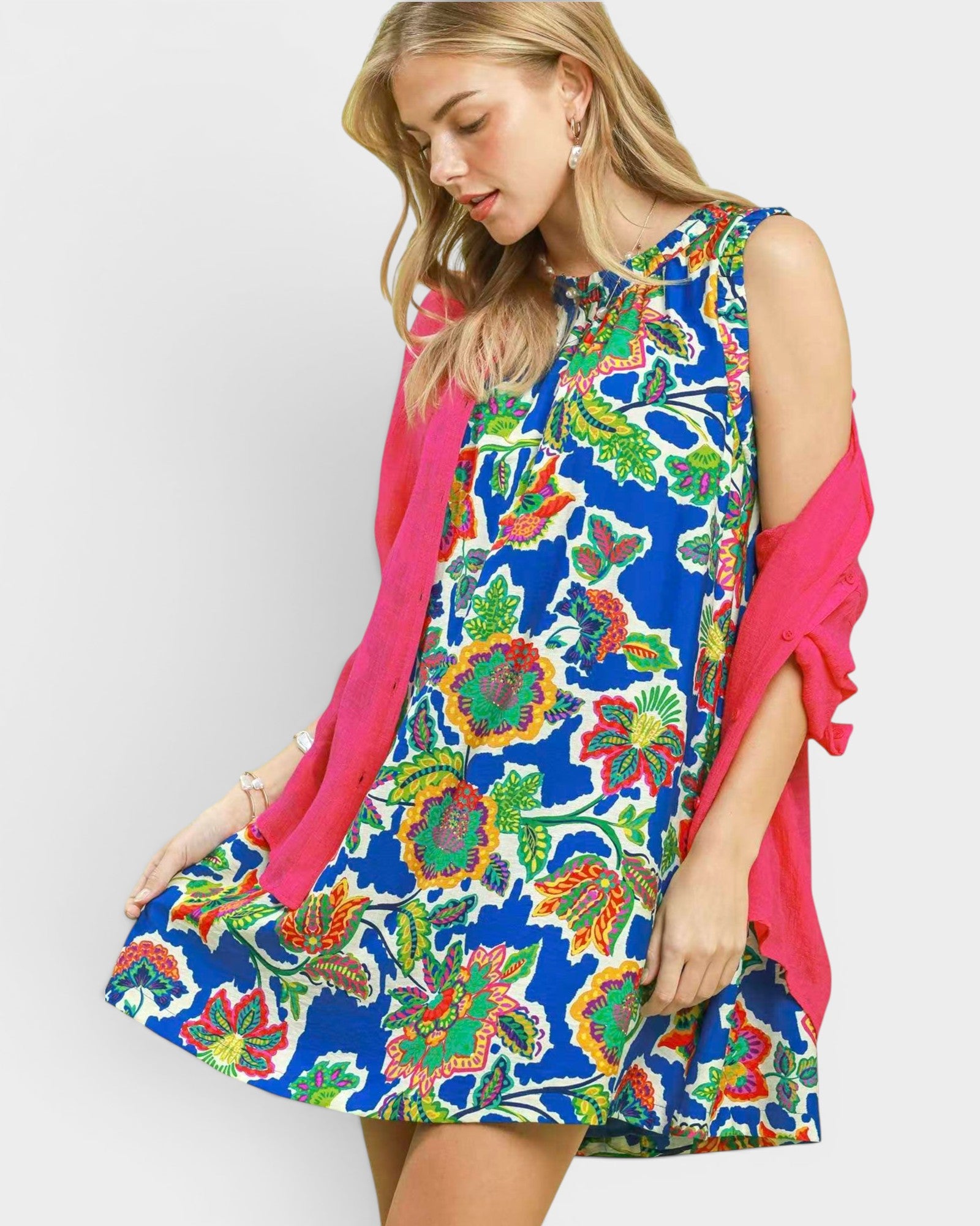 Woman wearing a colorful floral dress with a pink cardigan on a white background