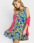 Woman wearing a colorful floral dress with a pink cardigan on a white background
