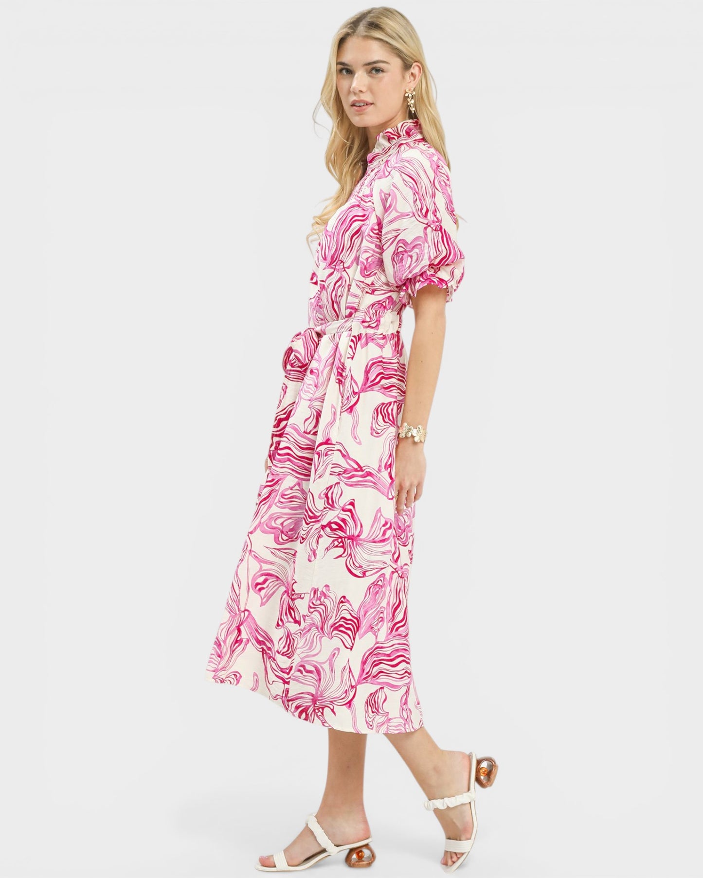 Woman wearing a pink and white patterned dress on a white background