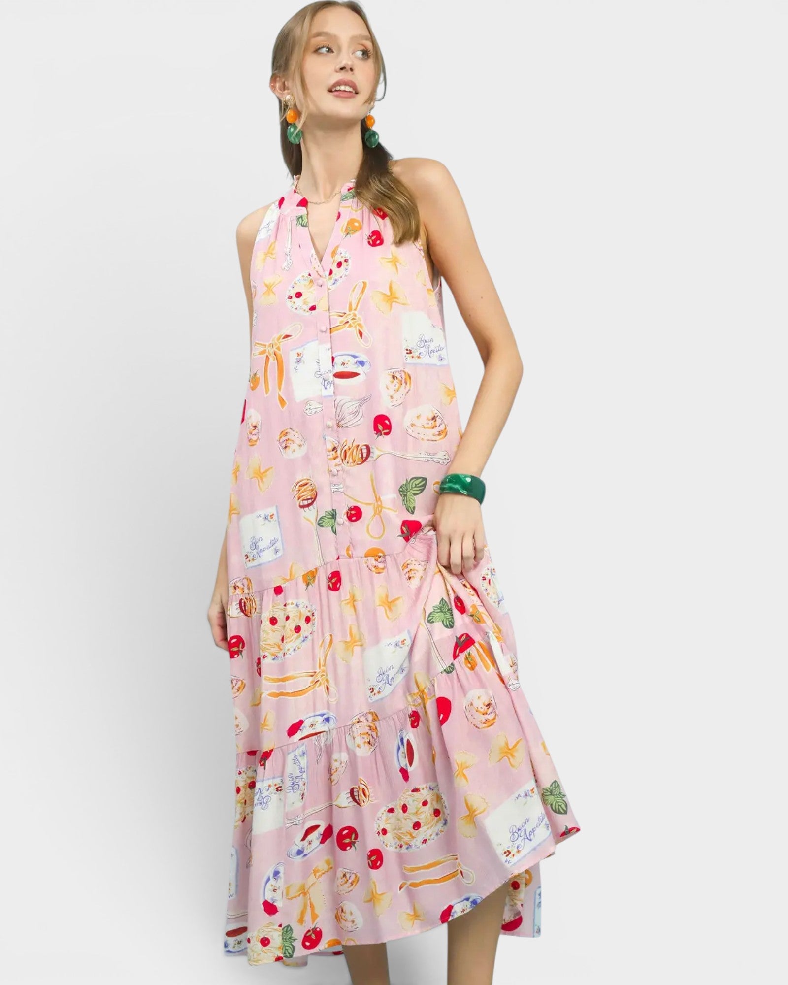Woman wearing a pink sleeveless dress with colorful patterns on a white background