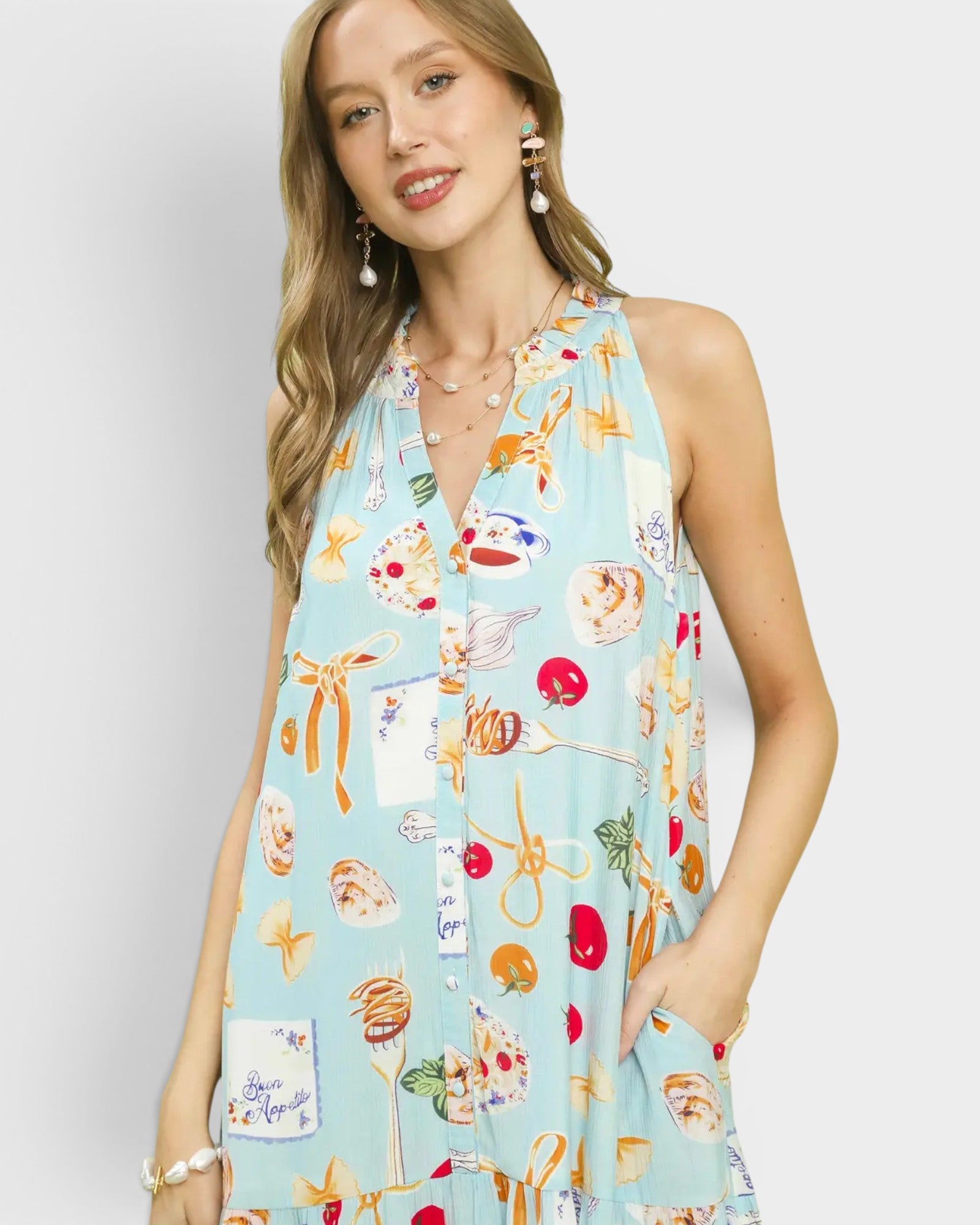 Woman wearing a light blue dress with colorful food print on a plain background
