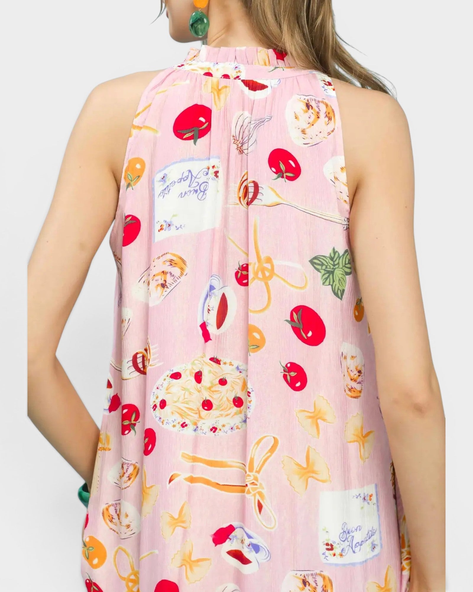 Woman wearing a sleeveless dress with colorful fruit and dessert pattern on a white background