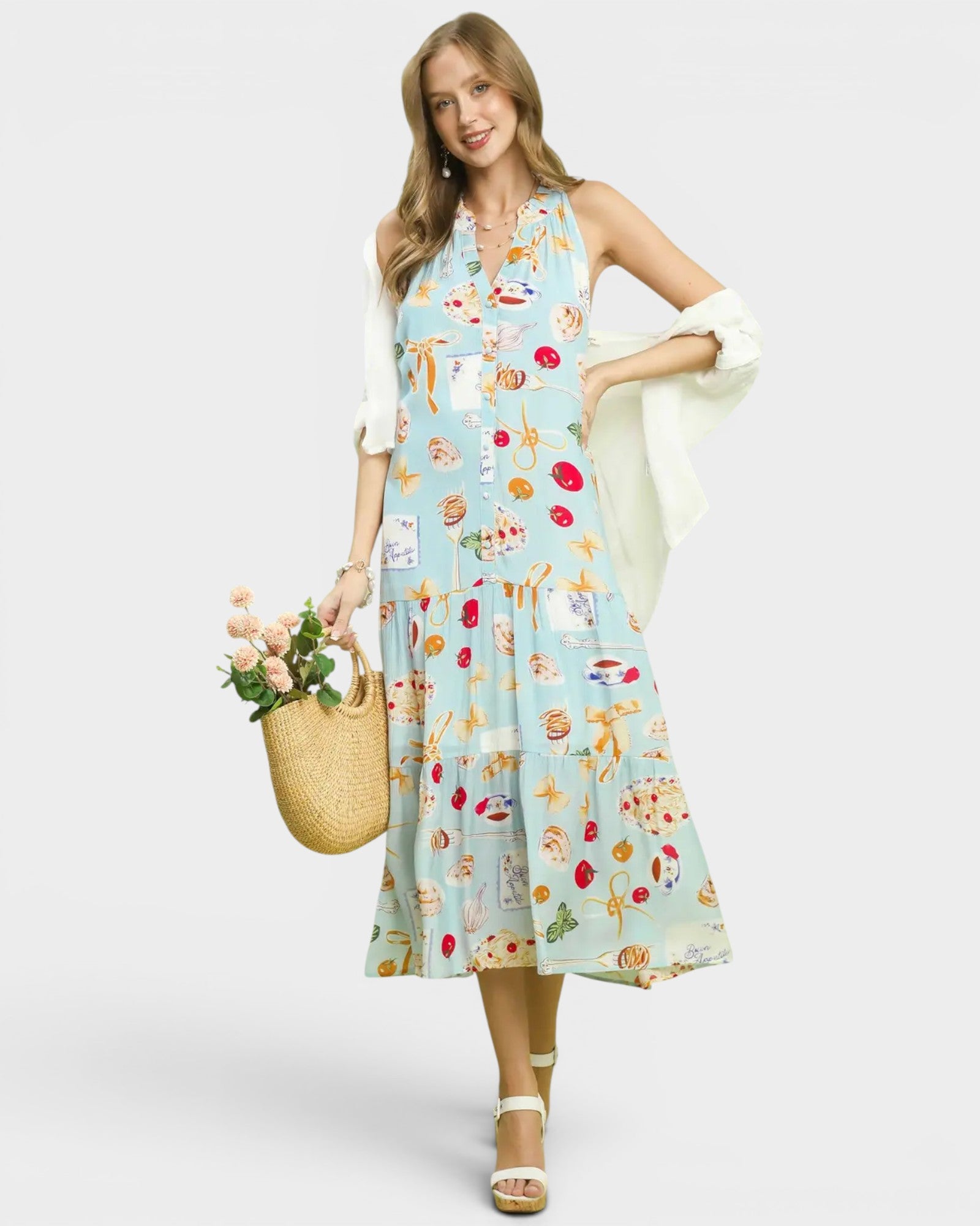 Woman wearing a floral dress holding a straw bag with flowers on a white background