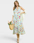Woman wearing a floral dress holding a straw bag with flowers on a white background