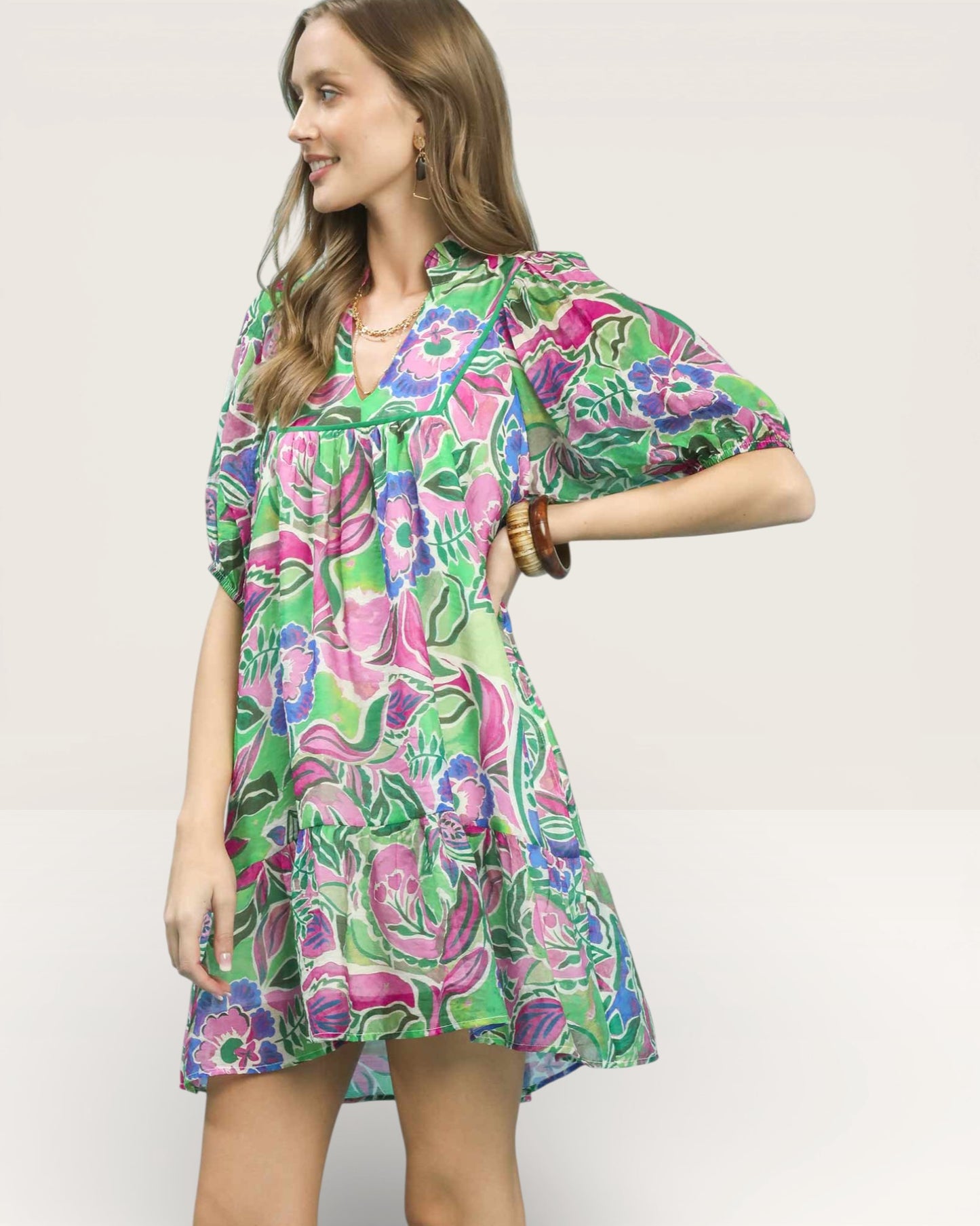 Woman wearing a colorful floral dress against a plain background