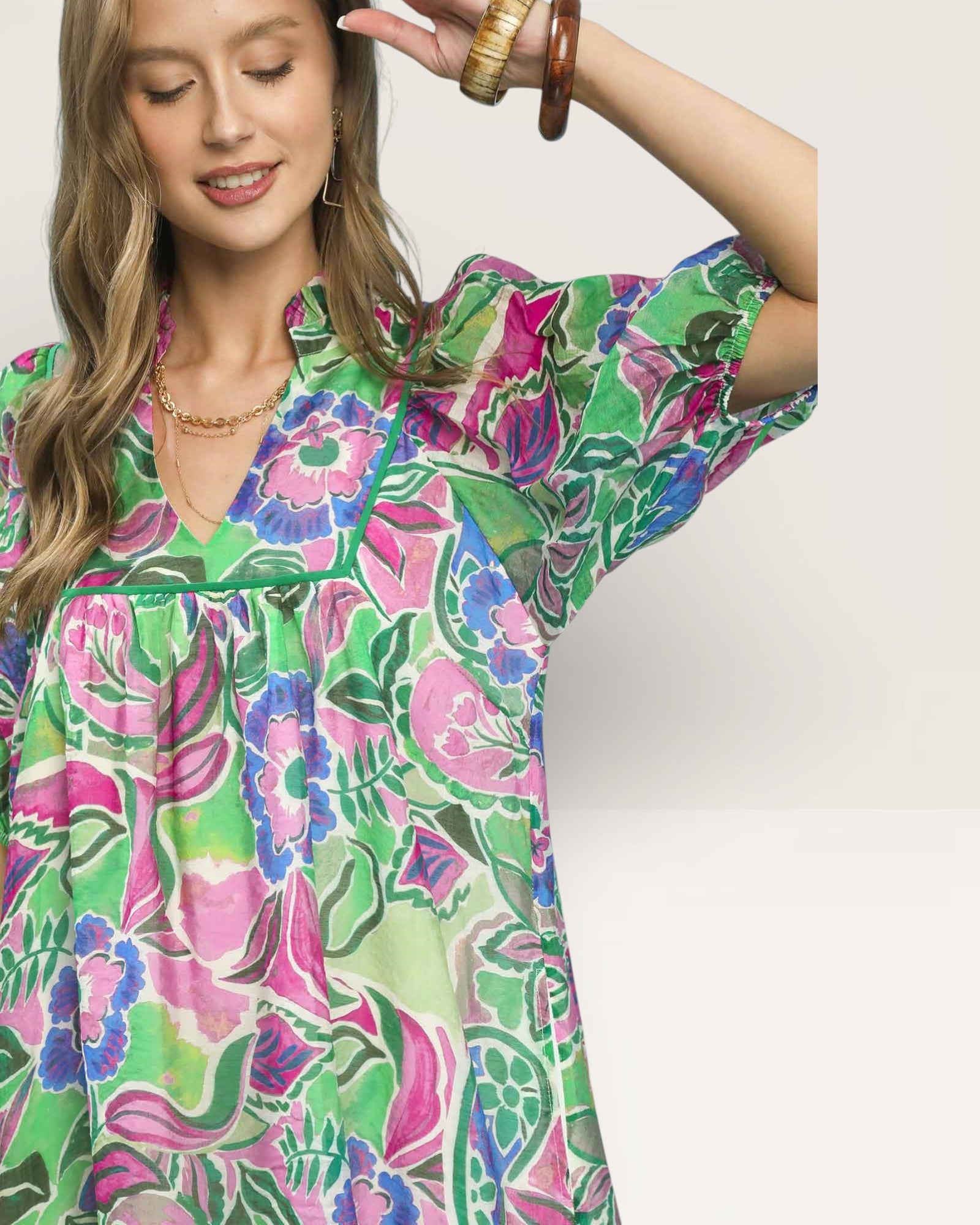 Woman wearing a colorful floral dress against a plain background